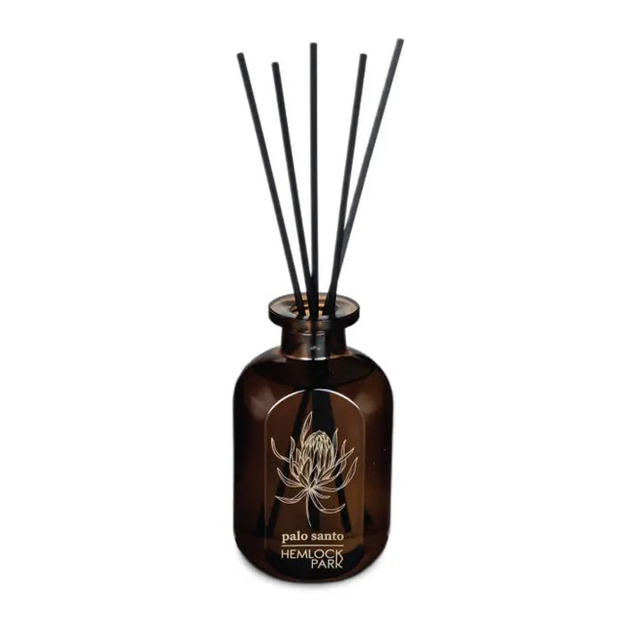 Amber apothecary jar reed diffuser with black reeds and palo santo label