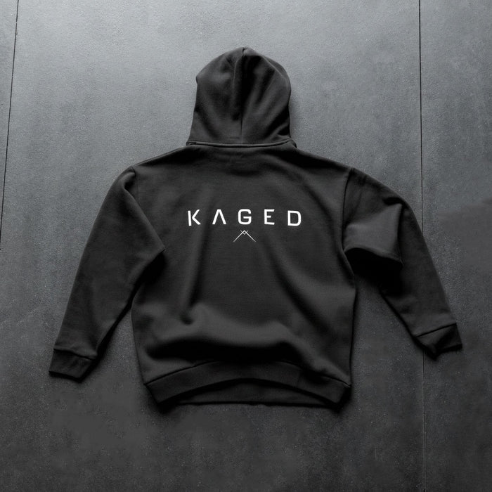 Back view of Ascent Hoodie showcasing white KAGED logo on black fabric on dark textured background