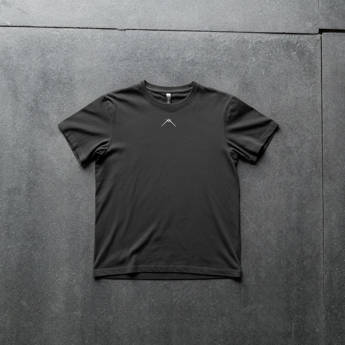 Front flat-lay of Ascent Tee showing small white Ascent logo at chest, black fitted cotton-spandex tee on dark textured background