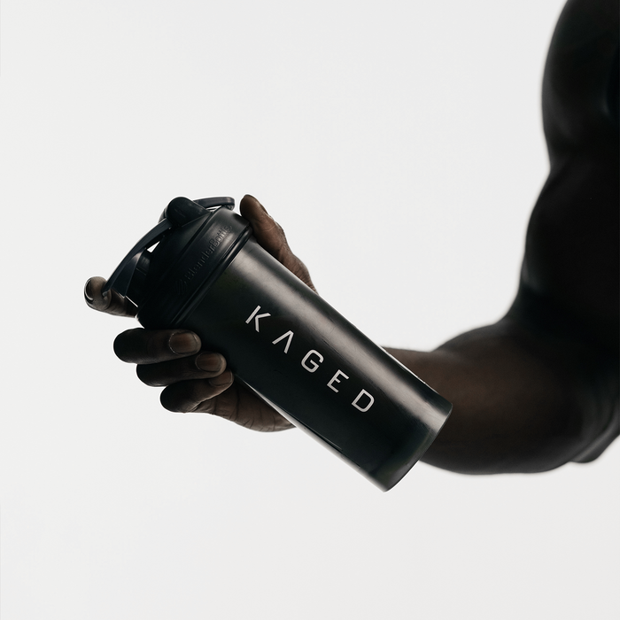 Angled view of Blender Bottle Classic 28 oz showing SpoutGuard lid, carry loop, and KAGED logo against a white background while held in a hand