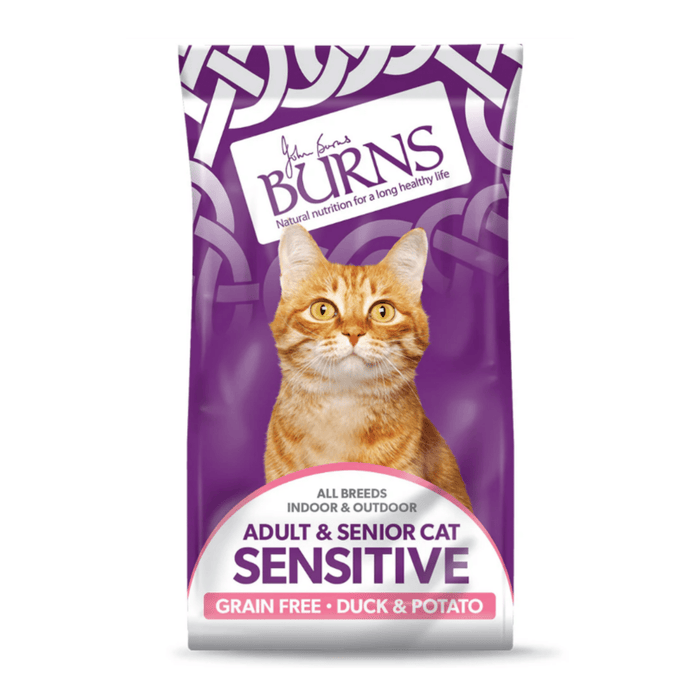 White background with a purple bag of Burns Sensitive Adult Cat food. On the bag an adult ginger tabby cat is pictured with text 'All Breeds, Indoor & Outdoor, Adult & Senior, Sensitive, Grain Free, Duck & Potato'.