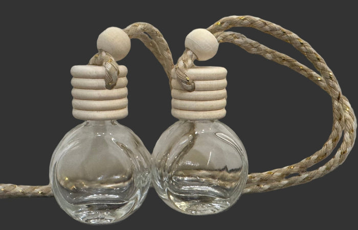 Two clear glass car air freshener 
bottles with wooden stoppers and rope on a gray surface.