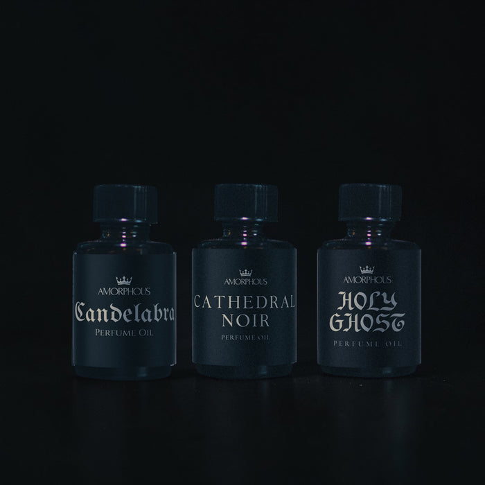 Three bottles of Amorphous perfume oil on a black background