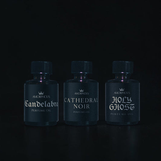 Three bottles of Amorphous perfume oil on a black background