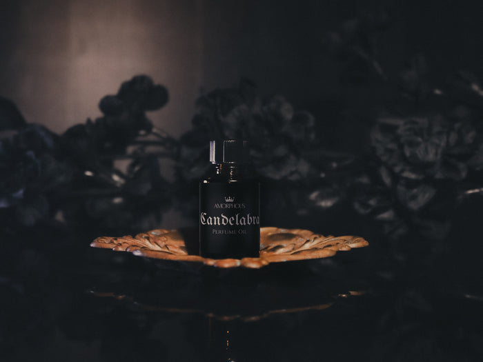 Dark glass bottle labeled 'Candelabra' on a reflective surface with a dark background