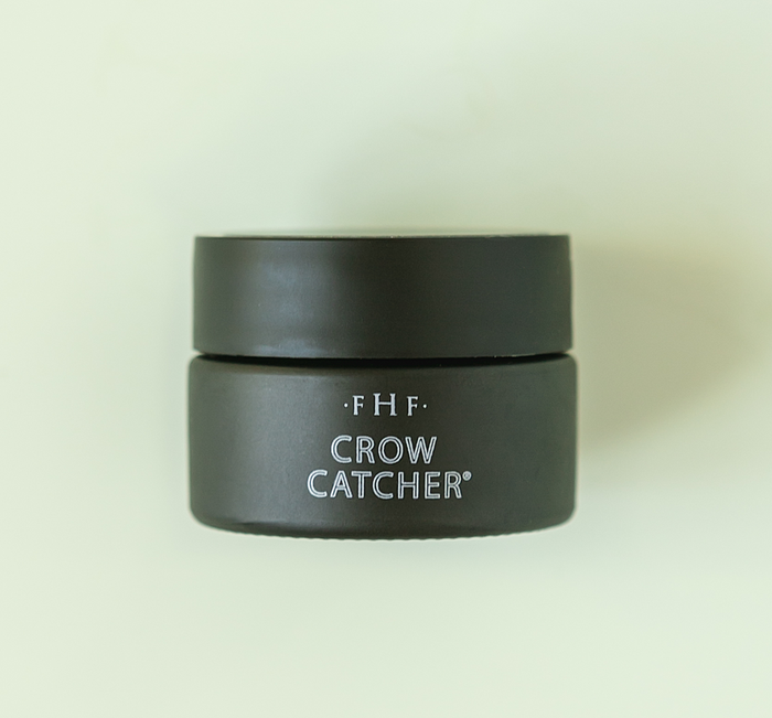 Minimalist black jar of Crow Catcher® Eye Transforming Serum | Farmhouse Fresh on a pale background, highlighting skincare product for eye care and rejuvenation.