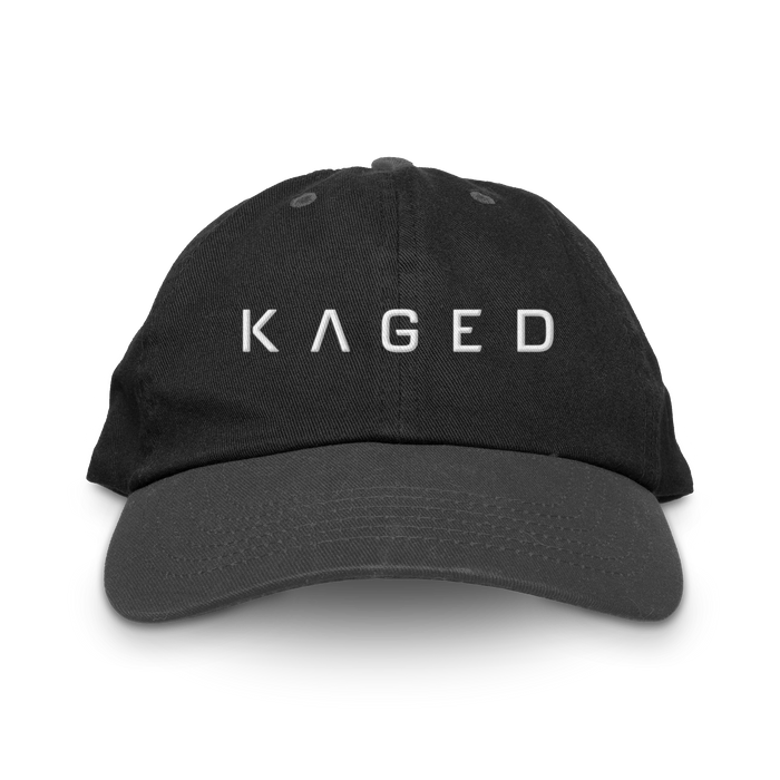 Front view of black dad hat showcasing white embroidered KAGED logo and curved brim on plain white background