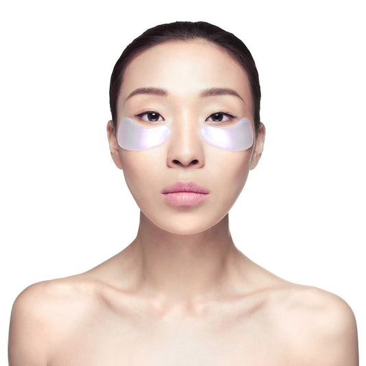 Young woman with smooth skin wearing Diamond Radiance Eye Mask - Single | Knesko under her eyes for skincare and wellness recovery.