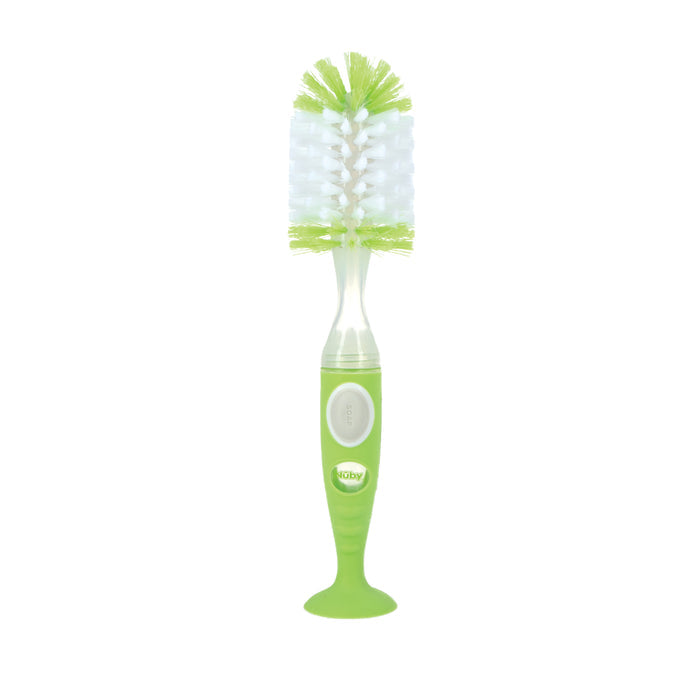The Easy Clean Soap Dispensing Brush with Suction Base features soft bristles, a sturdy handle with a circular button, and stands upright. Its green and white design displays the nûby brand name and is ideal for cleaning bottles.