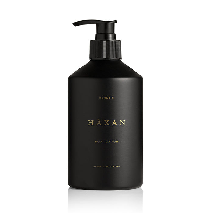 A matte black pump bottle of Häxan Heretic Body Lotion, featuring gold lettering on the front, set against a clean white background.