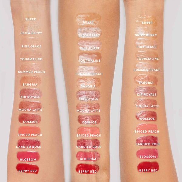 Swatches of twelve shades of Hydropure Hyaluronic Lip Gloss | Jane Iredale applied on three arms, showing glossy, sheer to bold colors ranging from neutrals and peaches to reds and berry tones.
