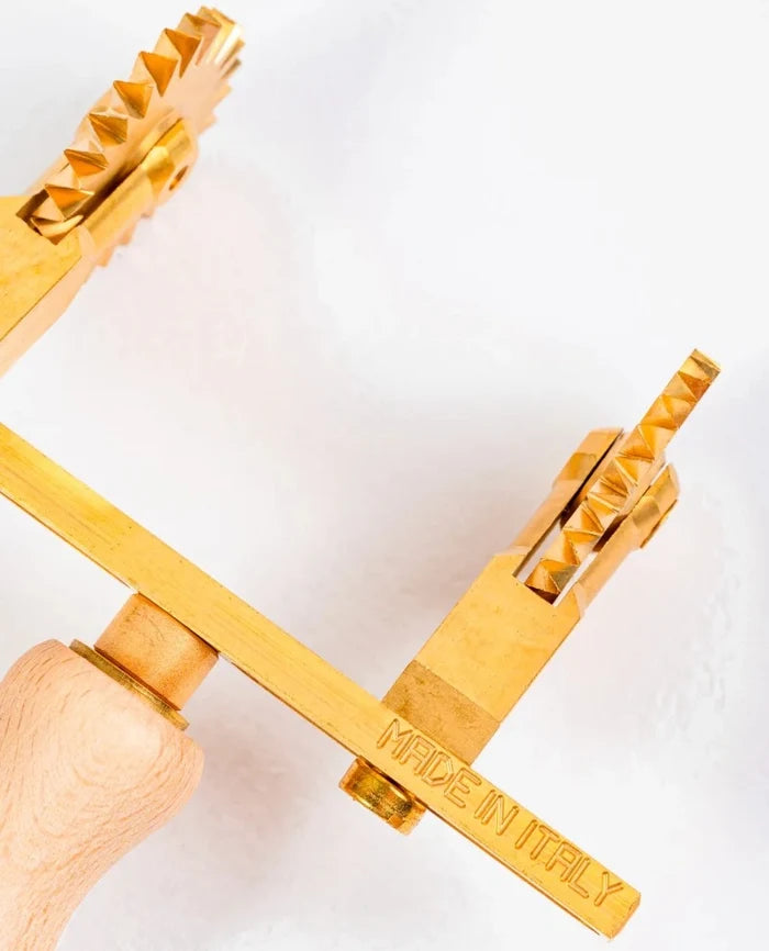 Gold-colored tool with 'MADE IN ITALY' engraving on a white background