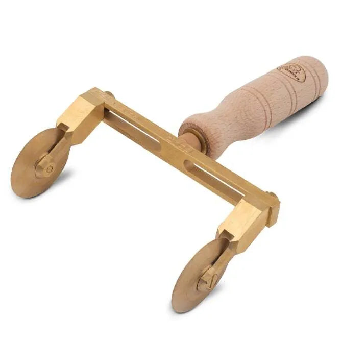 A professional adjustable ravioli cutter with two smooth wheels made of brass and a natural wood handle.