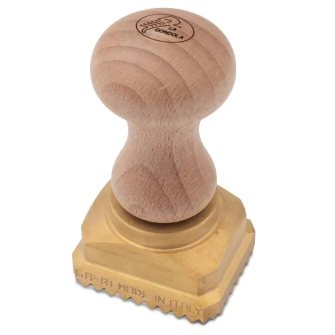 A rectangular brass pasta stamp with a wooden handle, featuring the text 'LA GONDELA' on the stamp surface on a white background.