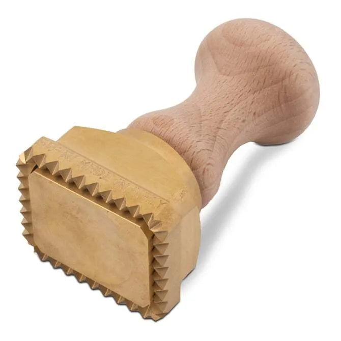 A rectangular brass pasta stamp with a wooden handle, featuring the text 'LA GONDELA' on the stamp surface on its side on white background.