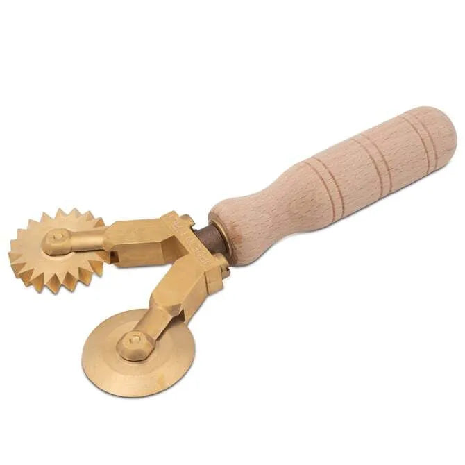 A handmade brass pasta cutter with a smooth and fluted wheel, featuring a wooden handle.