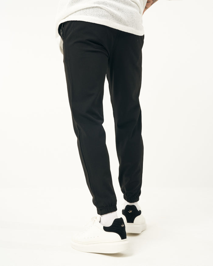 Martin Valen men's slim black jogger, front mid-body view focused on waist and fly under a white top
