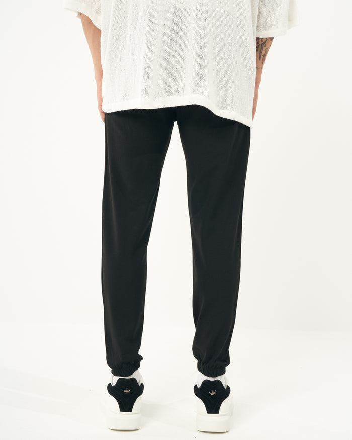 Martin Valen men's slim jogger black, leg-and-ankle view showing gathered cuffs and white sneakers