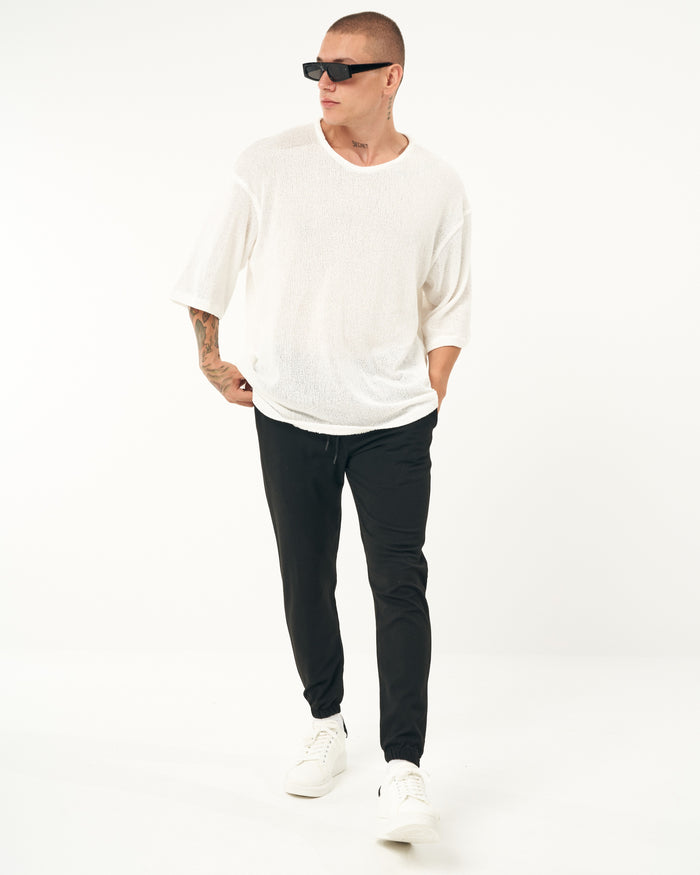 Martin Valen men's slim-fit black casual jogger, front view walking pose, hands near pockets and elastic cuffs, white sneakers