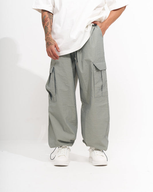 Martin Valen men's parachute fabric wide-leg cargo jogger in light sage green, mid-shot front view showing pocket and drawstring