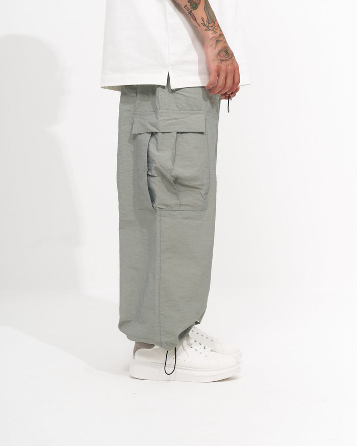 Martin Valen men's wide-leg cargo jogger in light sage green, lower-leg shot showing roomy hem and white sneakers