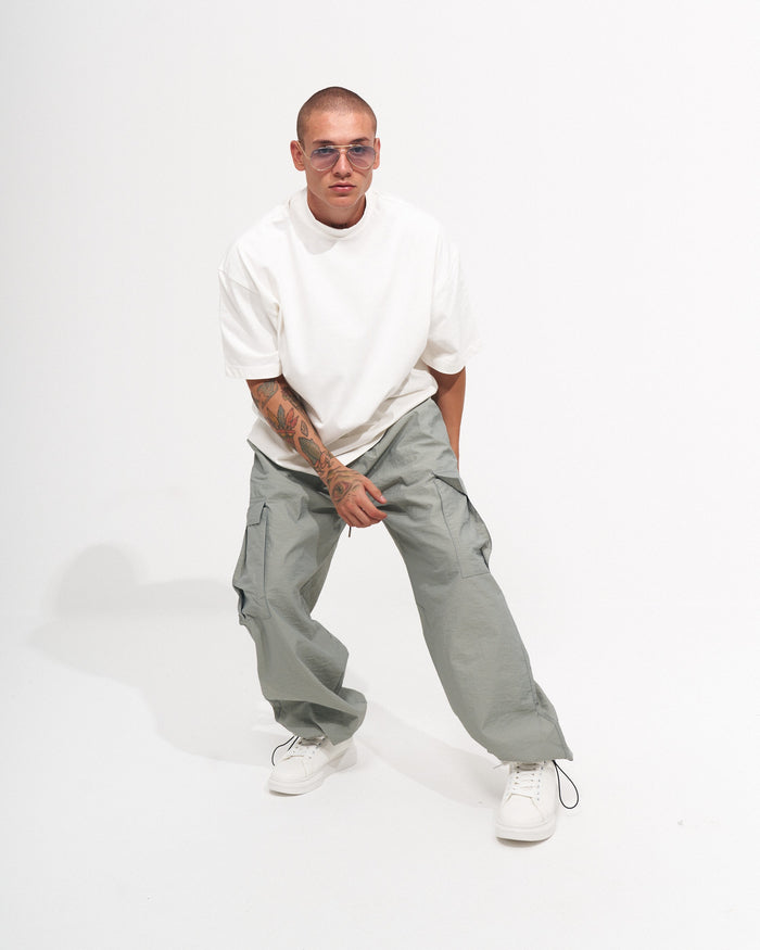 Martin Valen men's wide-leg cargo jogger in light grey-green close-up as model tightens the ankle drawcord