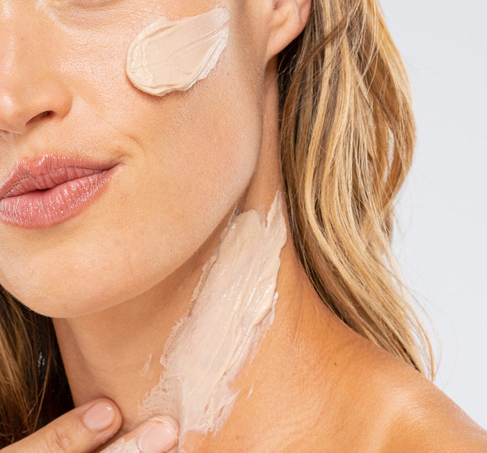 Close-up of a woman applying Mighty Tighty® Turmeric & Banana Tightening Mask | Farmhouse Fresh to her cheek and neck for skincare and tightening benefits.