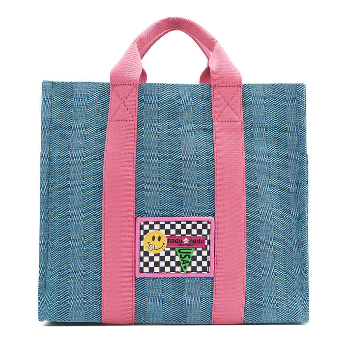 Your must-have carryall for school, weekends, and everything in between! Designed with a soft, relaxed silhouette, the Nodu Nadu Sawyer in Blue offers plenty of space to keep notebooks and loose essentials effortlessly organized—so you're always ready to grab and go! Light blue canvas paired with baby pink strap accents.