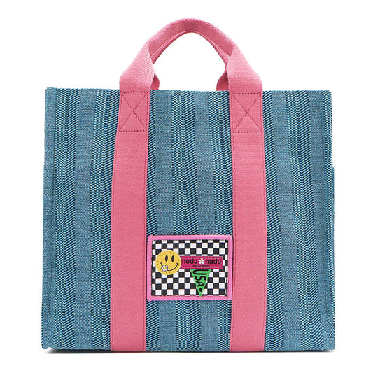 Your must-have carryall for school, weekends, and everything in between! Designed with a soft, relaxed silhouette, the Nodu Nadu Sawyer in Blue offers plenty of space to keep notebooks and loose essentials effortlessly organized—so you're always ready to grab and go! Light blue canvas paired with baby pink strap accents.