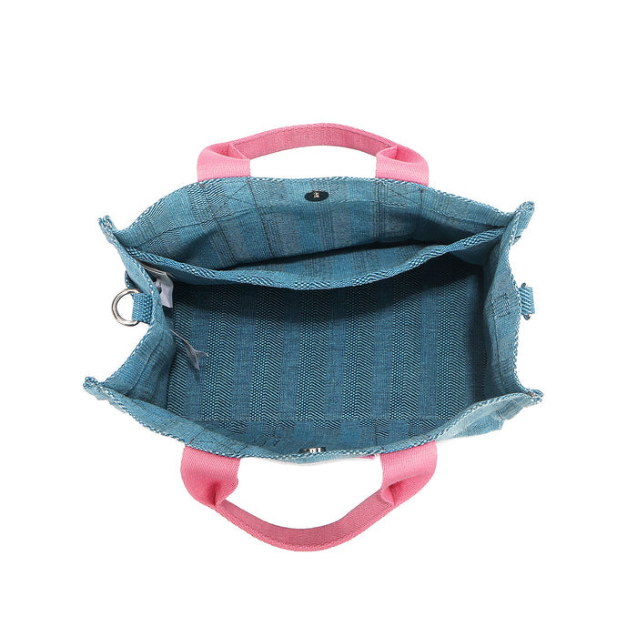 Nodu Nadu Sawyer Bag in Blue made of canvas with baby pink strap accents roomy interior opens up from its magnetic snap button closure to reveal an interior back slip compartment. Side D-rings for optional shoulder strap attachment provide varied carrying options.