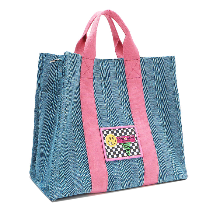 Front angle view of the Nodu Nadu Sawyer Bag in Blue. Crafted in durable canvas with side D-rings for optional shoulder strap attachment so you can wear this bag as a handbag, shoulder bag, or crossbody! It also features side slip pockets for a convenient touch.