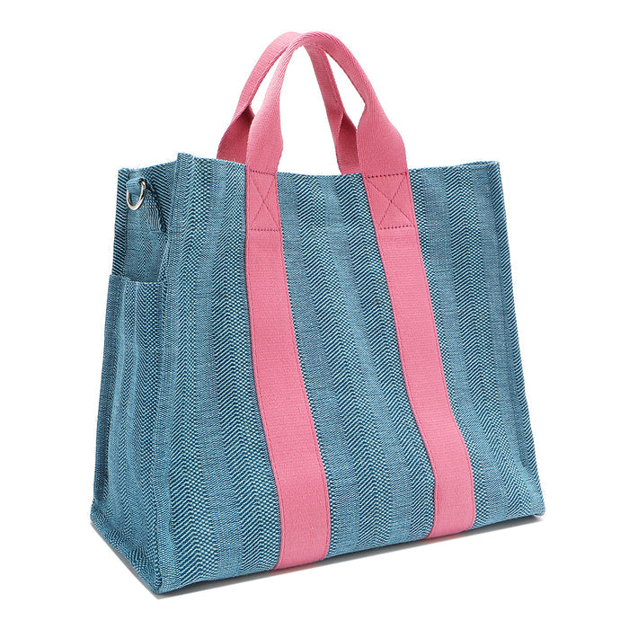 Back angle view of the Nodu Nadu Sawyer Bag in blue showcasing the side D-rings which allow you to attach the optional and adjustable shoulder strap to wear this bag across the body or around the shoulder, perfect for long-term wear and comfort. Side angle also shows the side slip pocket for a convenient touch.