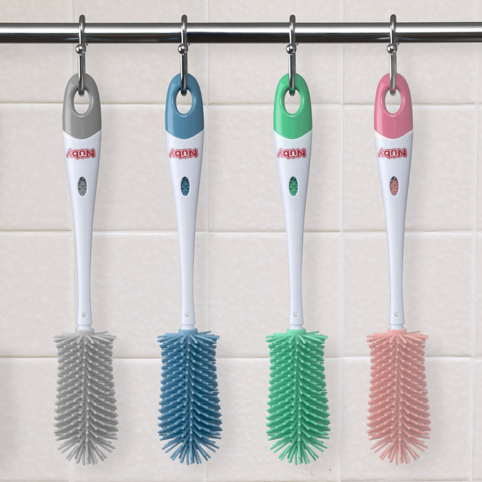 Four Non-Scratch Silicone Bristle Bottles with white handles and bristles in gray, blue, green, and pink hang from hooks on a metal rod against a tiled wall.