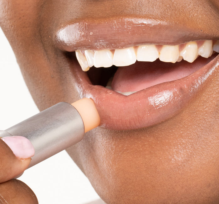 Close-up of a person applying Orange Mood Fruit™ Lip Therapy | Farmhouse Fresh lip balm to moisturize and protect lips for smooth, healthy skin.