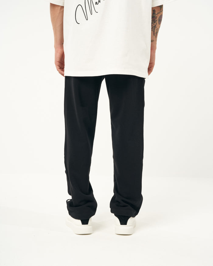 Martin Valen oversized black baggy jogger mid-length view showing legs, side press-studs and white sneakers