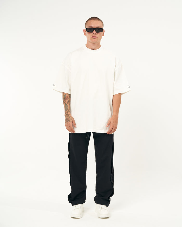 Martin Valen oversized black baggy jogger, side view showing the row of silver press studs along the leg