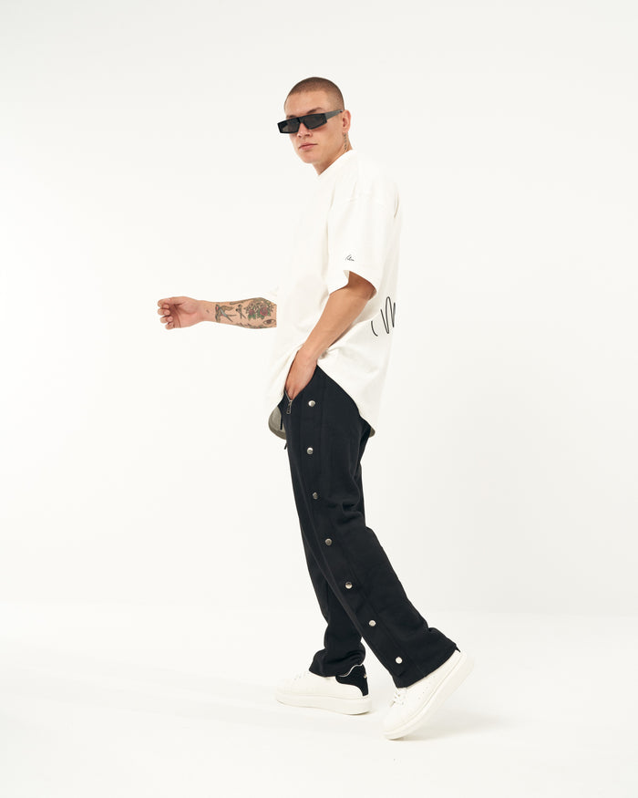 Martin Valen oversized black baggy jogger, side view showing metal press studs on the leg