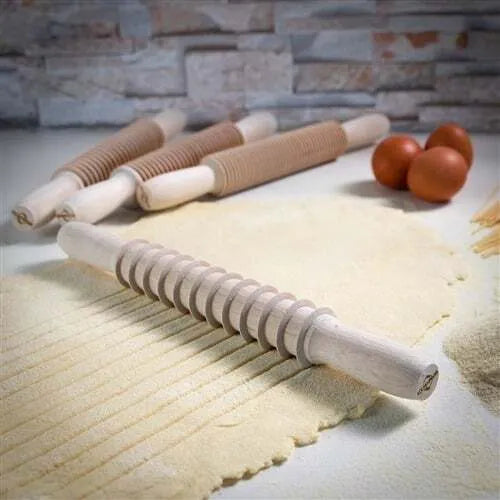 A wooden pasta cutter with a rolling pin shape designed for cutting spaghetti from rolled-out pasta dough.