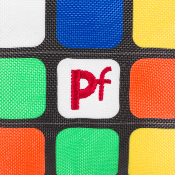 Close up of retro style cube style dog toy with blue, green, orange, yellow and white squares with stitch detail 'PF' on a middle white square on a white background.