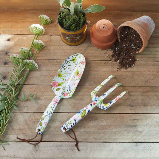 Floral-patterned gardening tools on a wooden surface with plants and pots.