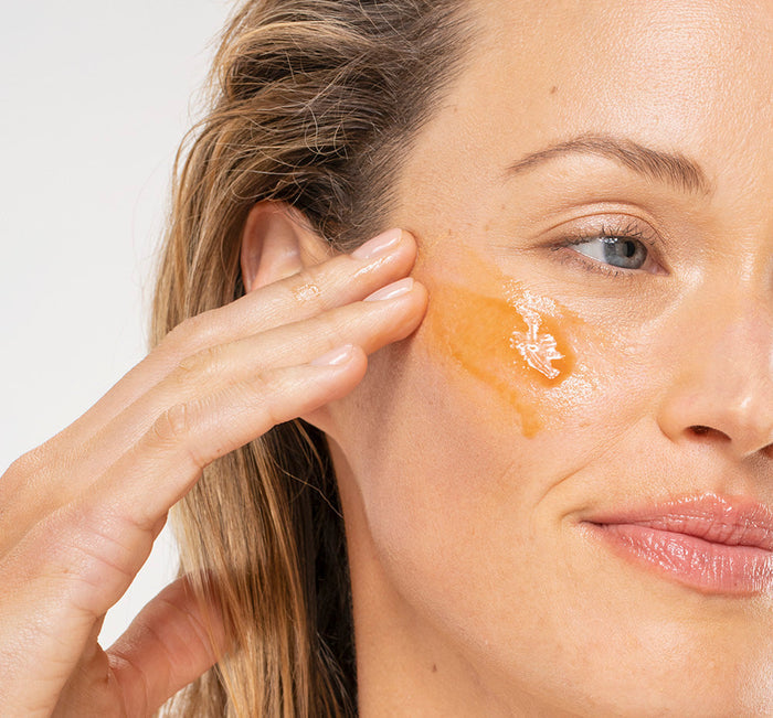 Woman gently applying Wine Down® Overnight Super Antioxidant Recovery Serum | Farmhouse Fresh to her cheek, showcasing skincare routine and glowing skin.